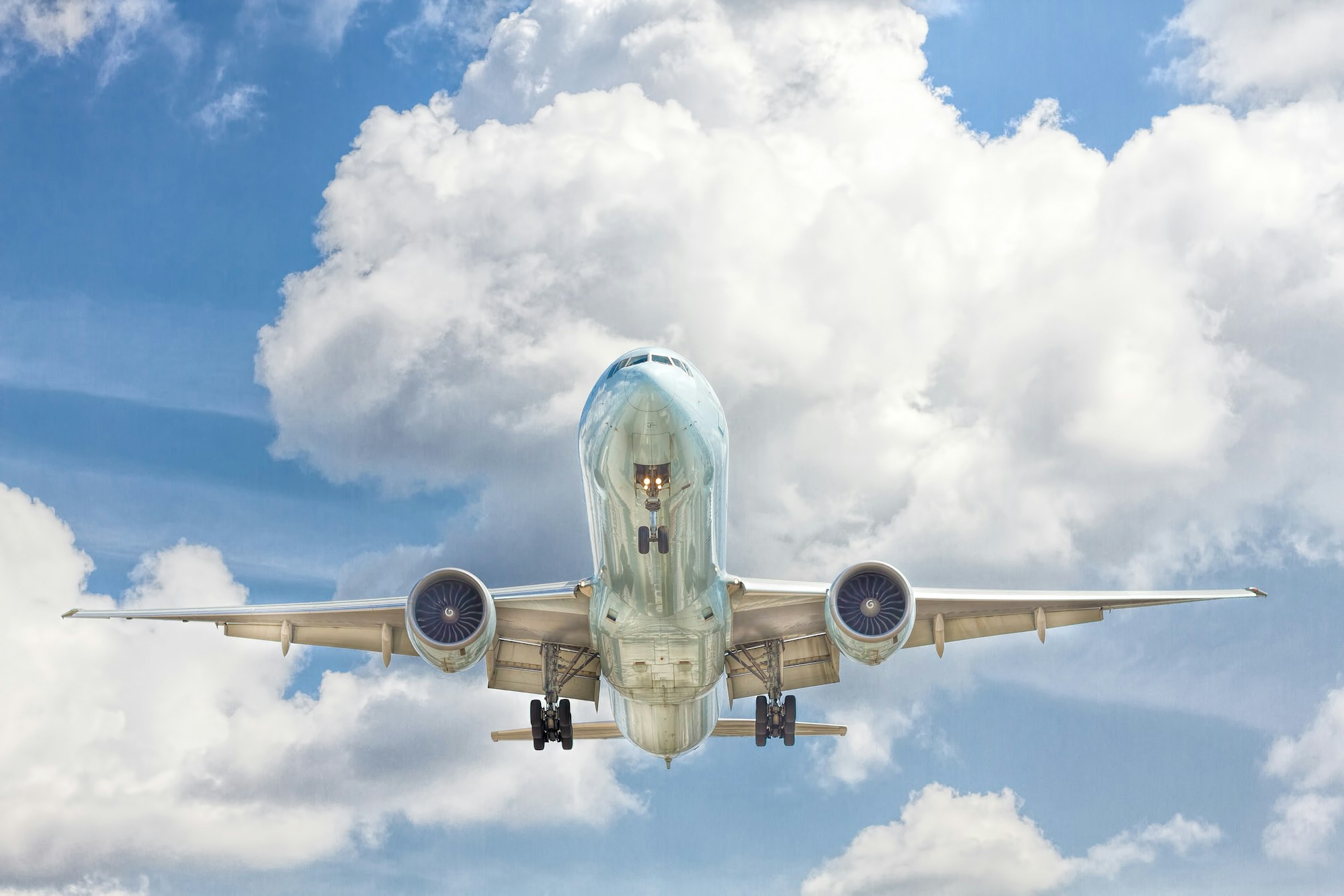 Commercial aircraft climbing through bright cumulus clouds
